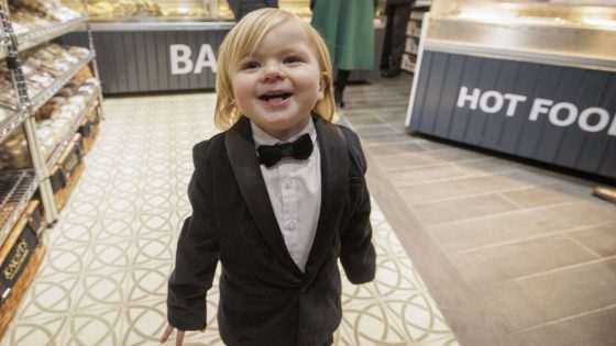 Dapper toddler in tuxedo steals show as Queen visits his dad’s bakery in Belfast | UK News – MASHAHER